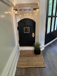 a black door with a welcome sign above it and a potted plant next to it