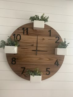 a wooden clock with white planters and numbers on the face, hanging from a wall