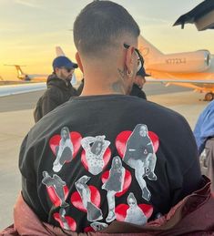 a man with tattoos on his back standing in front of an airplane