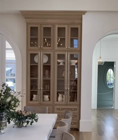 a dining room table with chairs and vases on it in front of an arched doorway