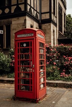 a red phone booth sitting in front of a building