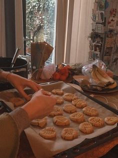 a person is baking cookies on a pan in front of an open window with curtains