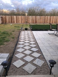 an outdoor patio area with stone pavers and graveled walkway leading to the back yard