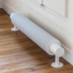 a white heater sitting on top of a hard wood floor next to a wall