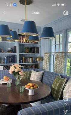 a dining room table with blue chairs and bookshelves on the wall behind it