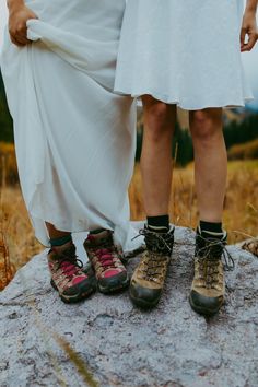 two people standing next to each other on top of a rock