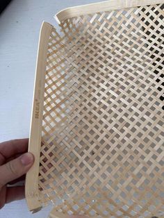 a person is holding a basket made out of plywood wood and plastic material with holes in it