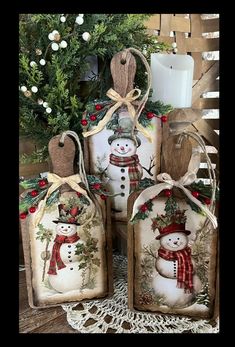 three snowmen with hats and scarfs are sitting next to each other in front of a christmas tree