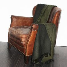 an old leather chair with a blanket draped over it