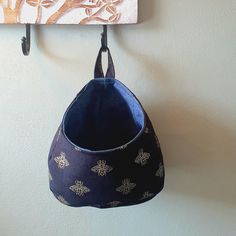 a blue purse hanging from a hook on a wall next to a painting with flowers