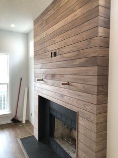 an empty living room with a fireplace and wood paneling on the wall behind it