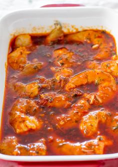 a red dish filled with shrimp and sauce