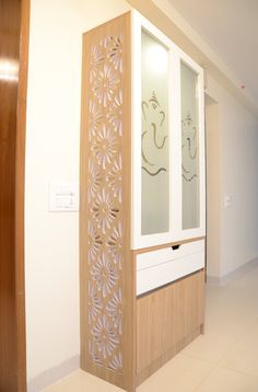 an empty room with a wooden cabinet and decorative glass panels on the door, in front of a white wall