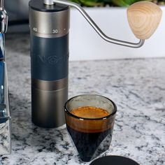 an espresso machine next to a cup of coffee on a marble counter top