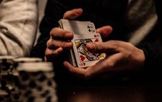 two hands holding playing cards on a table