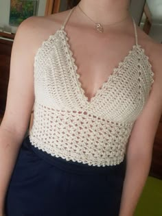 a woman wearing a white crochet top standing in front of a mirror