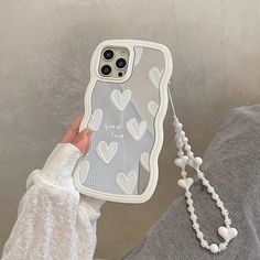 a person holding up a phone case with hearts on it and a chain attached to the back