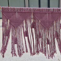 a purple wall hanging with tassels and beads on the outside, in front of a building