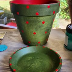 a green planter sitting next to a red bowl on top of a table