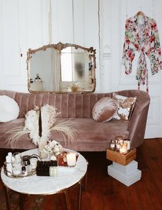 a living room filled with furniture and decor on top of a wooden floor next to a white wall