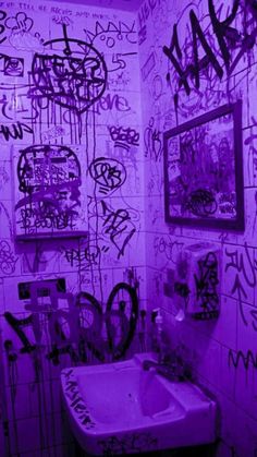 a bathroom with graffiti on the walls and a sink in the foreground is lit by purple light