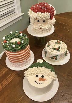 four decorated cakes sitting on top of a wooden table