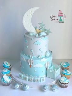 a blue and white cake with cupcakes around it