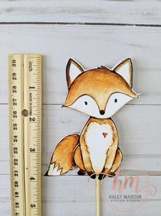 a wooden stick with a drawing of a fox on it next to a measuring ruler