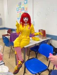 a clown dressed in yellow sitting at a table