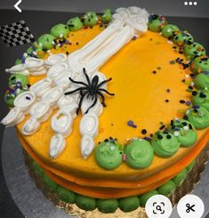 a halloween cake decorated with green and orange icing, sprinkles and a spider on top