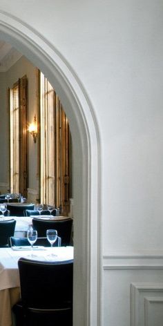 an archway leading into a restaurant with tables set up for dinner and wine glasses on the table