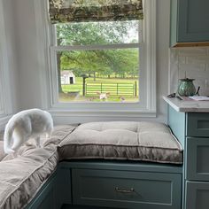 a white dog standing on top of a window sill next to a bed in a kitchen