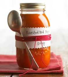 a glass jar filled with red liquid on top of a wooden table next to a spoon