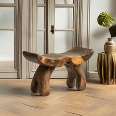 a wooden bench sitting on top of a hard wood floor next to a potted plant