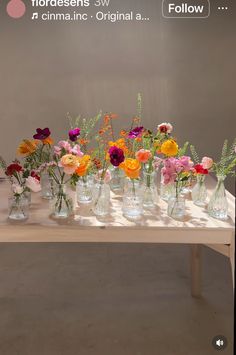 there are many vases with flowers in them on the table and one is empty