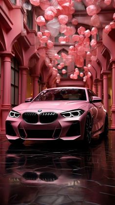 a pink car parked in front of a building with red balloons hanging from the ceiling