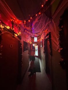 a woman walking down a hallway covered in lights and streamers, with her back turned to the camera