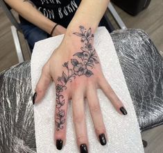 a woman's hand with flowers tattooed on it