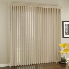 a living room with a yellow chair and large window covered in vertical blind blinds that are closed