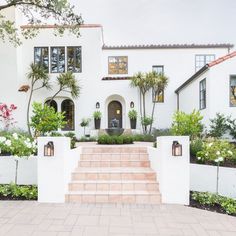 a white house with steps leading up to the front door and trees on either side