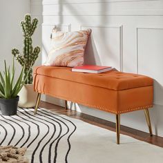 an orange bench sitting on top of a white rug next to a potted plant