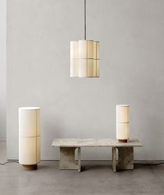 three lamps hanging from the ceiling next to a bench and table with a lamp on it