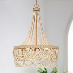 a chandelier with pearls hanging from it's sides in a room that has white walls and windows