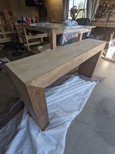 a wooden bench sitting on top of a piece of plastic in a room filled with furniture