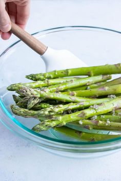 asparagus in a glass bowl with a wooden spoon