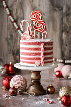 a red and white cake sitting on top of a table next to christmas ornaments with candy canes