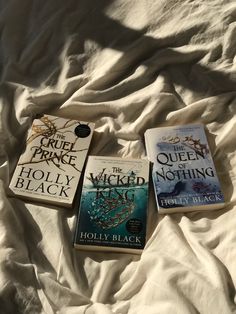 three books laying on top of a bed next to each other