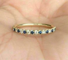 a gold ring with blue and white stones on it's side, in the palm of someone's hand