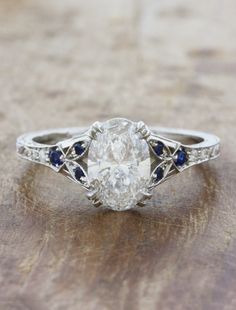 caption:Shown with 1.42ct oval diamond Sapphire Side Stone Engagement Ring, Diamond And Blue Sapphire Ring, Engagement Rings With Blue Accents, Oval Wedding Ring With Side Stones, Oval Diamond With Sapphire Side Stones, 1800 Engagement Ring, Unique Oval Diamond Ring, Silver And Blue Engagement Ring, Engagement Rings With Engraved Bands