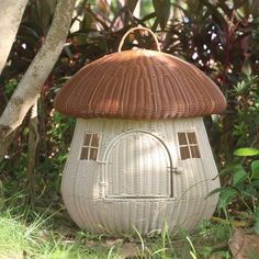 a house made out of wicker sitting in the grass next to trees and bushes